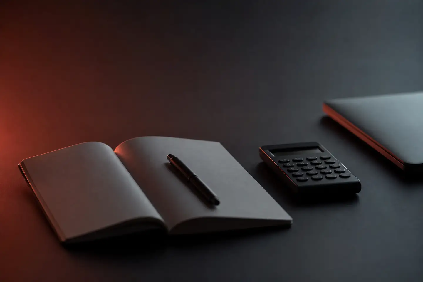 Een notitieboek met pen en een rekenmachine op een donker bureau