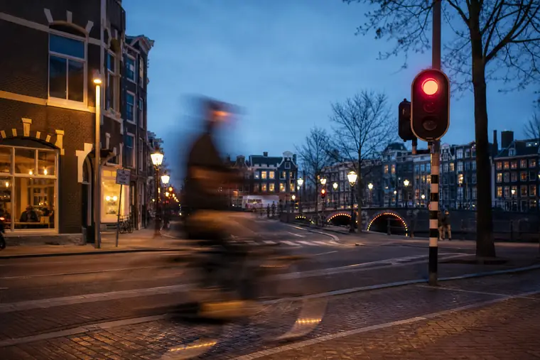 Een fietser die als beweging langs een Nederlandse straat schiet in het avondlicht